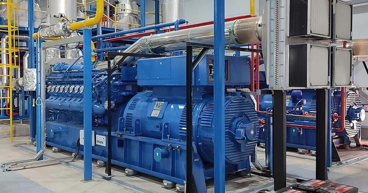 Two MWM TCG 3020 V20 gas engines in signature blue at Chilanzar District Heating Plant in Uzbekistan; one engine prominently in the foreground, the second partially visible in the background inside a large industrial hall.