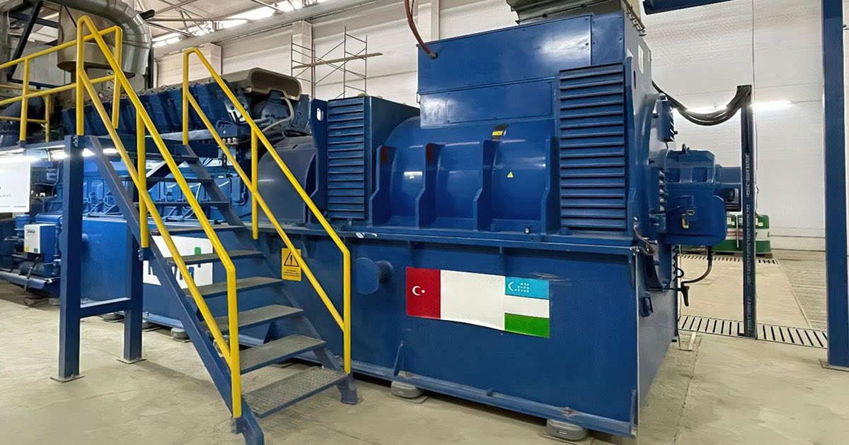 MWM TCG 2032B V16 gentset in signature blue at FT TEXTILE factory in Namangan, Uzbekistan, with MWM logo in the background and Uzbek and Turkish flags connected by a white field in the foreground.